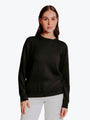 Woman wearing a black sweater and white pants on a white background