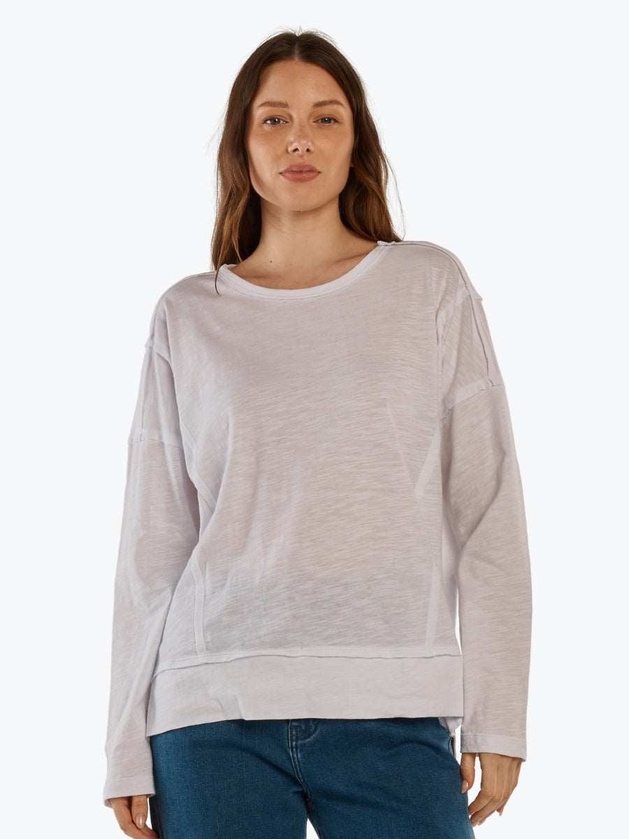 Woman wearing a light gray sweatshirt and blue jeans on a white background