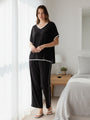 Woman wearing a black jersey set with white stripes standing in a bedroom.