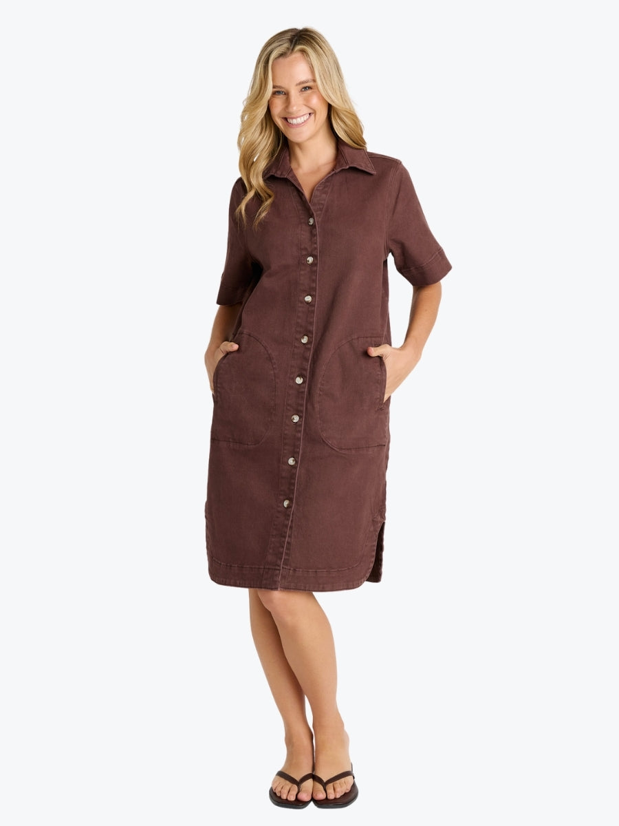 A woman modeling a brown short-sleeve button-front shirt dress with side pockets, standing against a light gray studio background.
