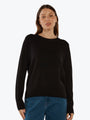 Woman wearing a black sweater and blue jeans on a white background