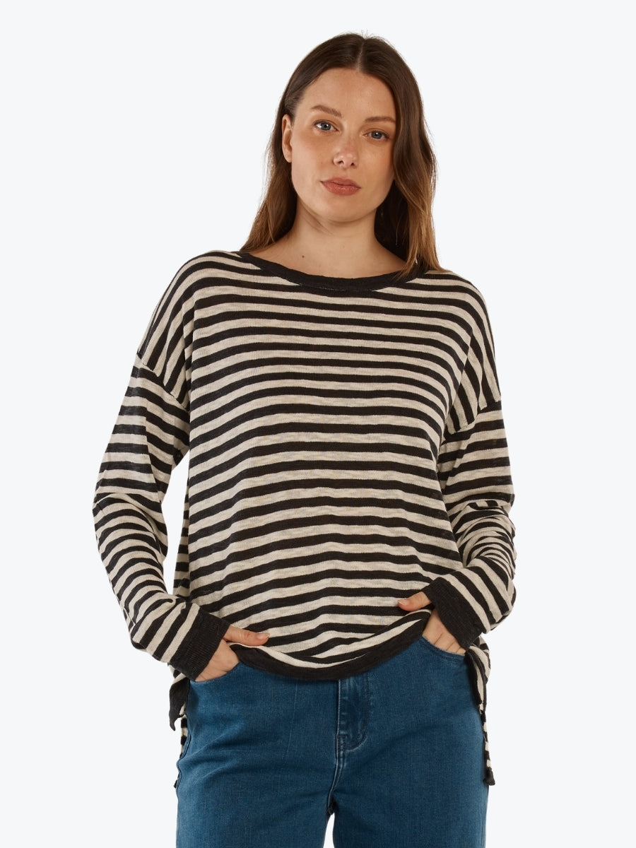 Woman wearing a black and white striped sweater with blue jeans on a white background
