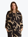 Woman wearing a black and beige patterned blouse on a white background
