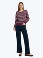 Woman wearing a striped sweater and dark pants on a white background