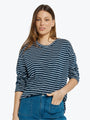 Woman wearing a blue and white striped shirt with blue jeans on a light gray background