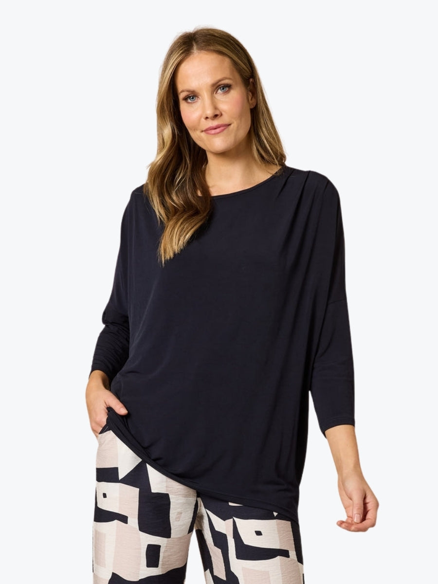 Woman wearing a navy top and patterned pants on a white background