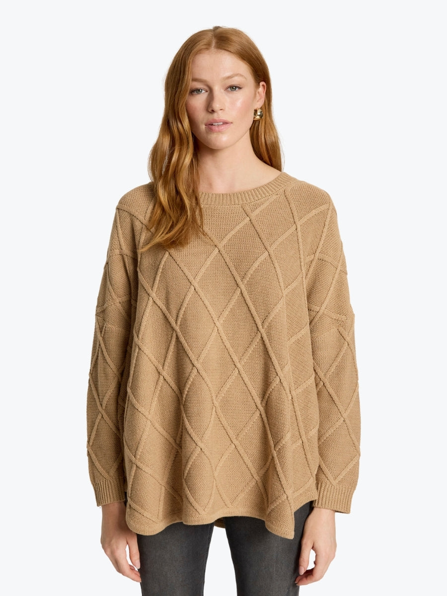 Woman wearing a beige cable knit sweater on a white background