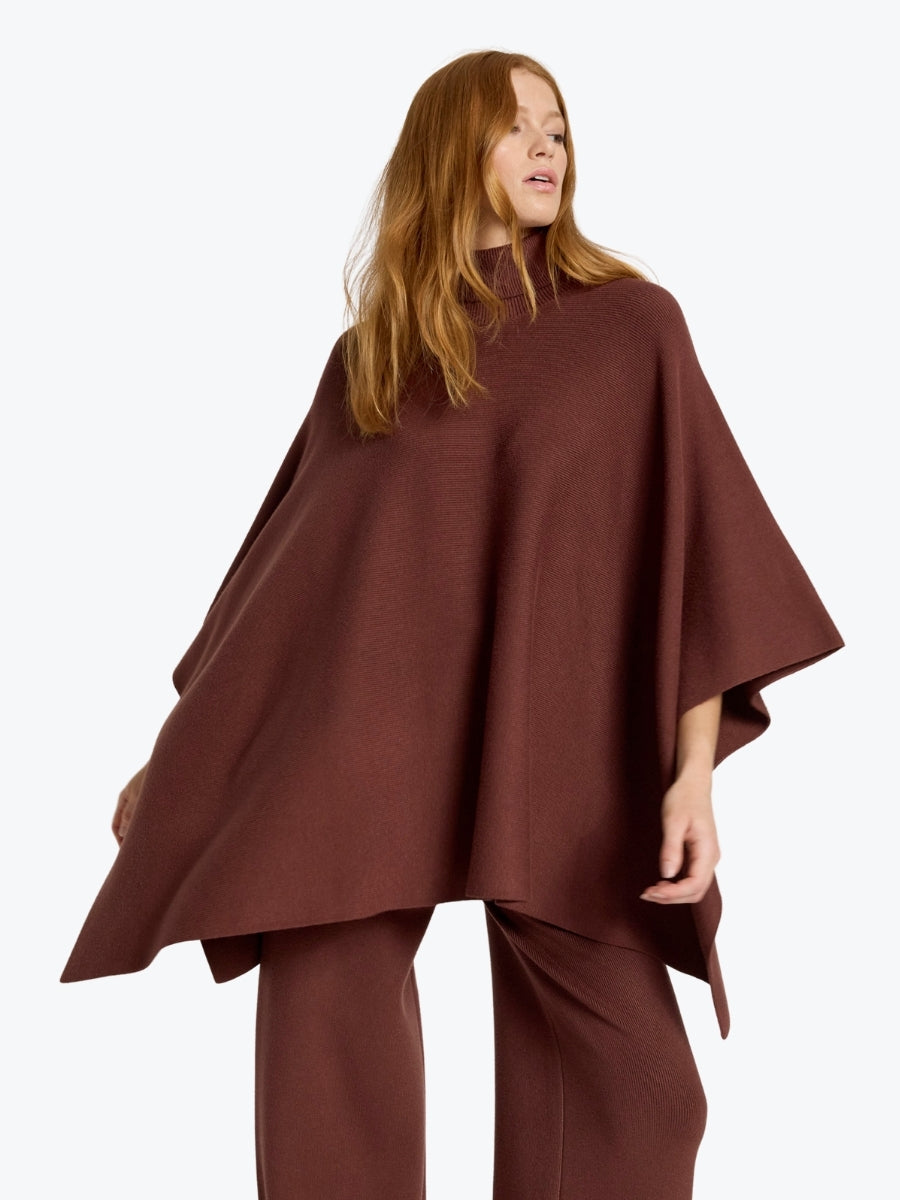 Woman wearing a brown poncho and pants on a white background