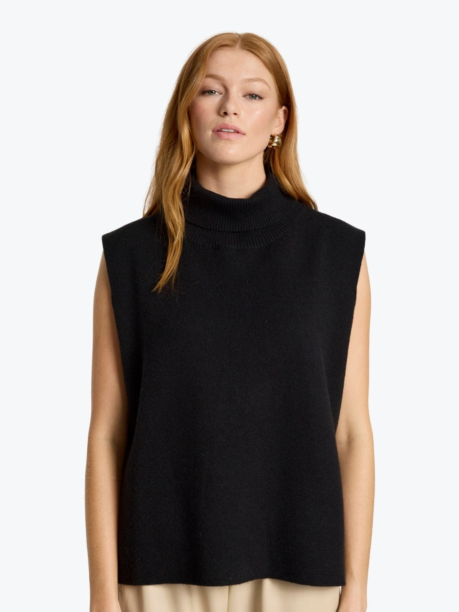 Woman wearing a black sleeveless turtleneck top on a white background