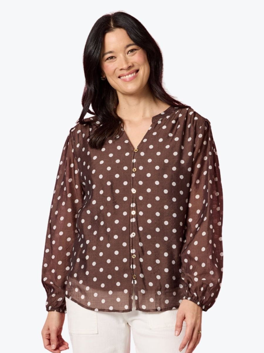 Woman wearing a brown blouse with white polka dots on a white background