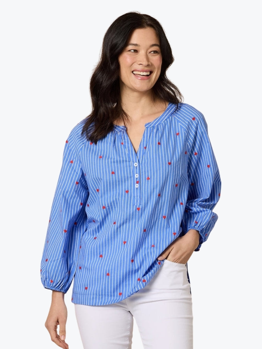 Woman wearing a blue striped shirt with small red patterns on a white background