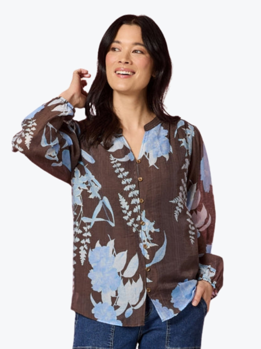 Woman wearing a brown floral blouse with blue flowers on a white background