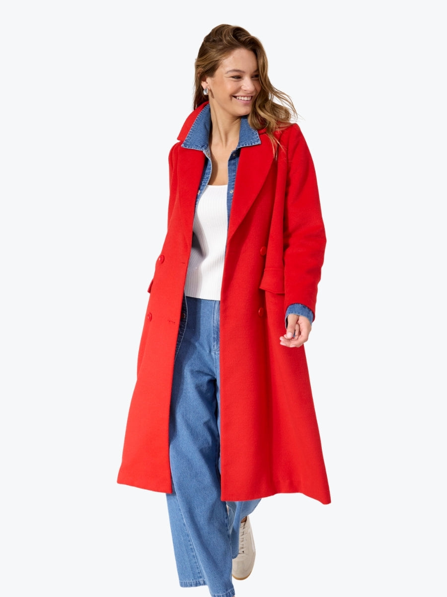 Woman wearing a red coat with blue lining on a white background