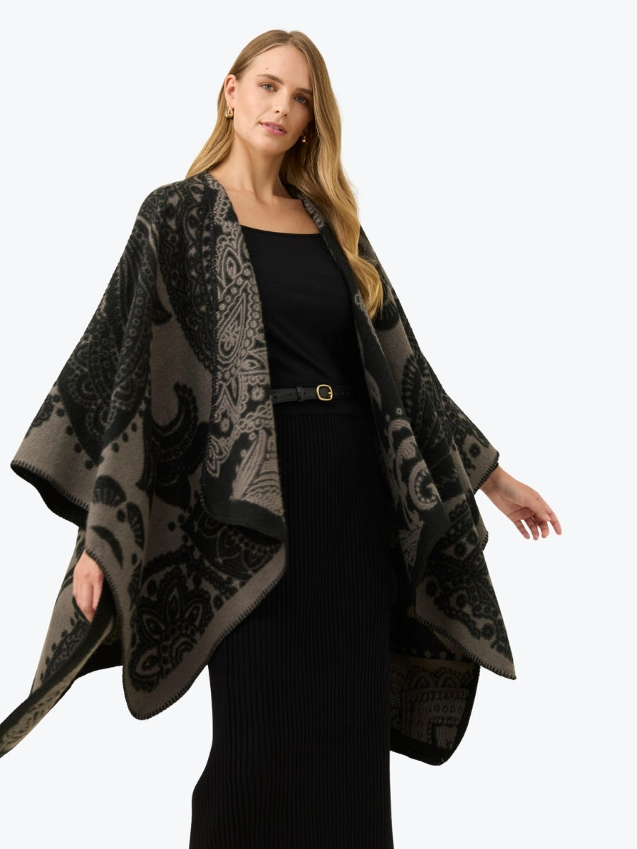 Woman wearing a black and gray patterned poncho on a white background