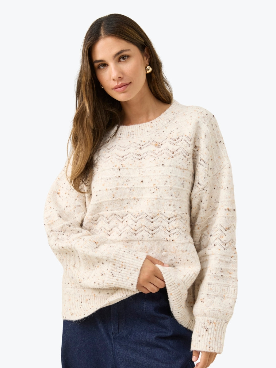 Woman wearing a cream knitted sweater on a white background