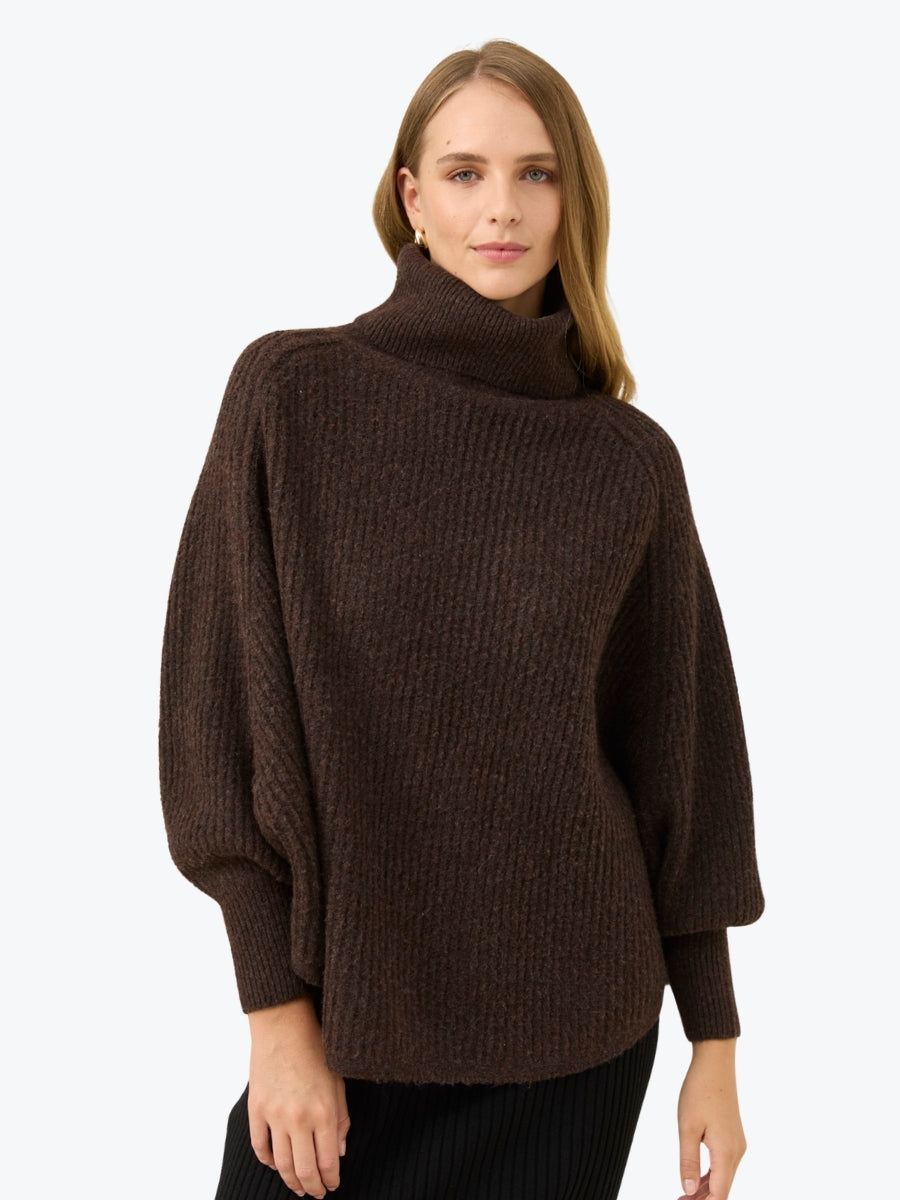 Woman wearing a brown turtleneck sweater on a white background
