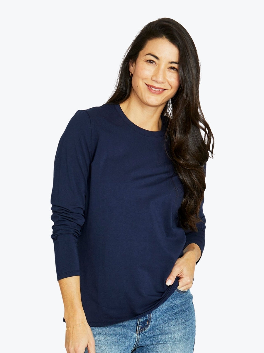 Woman wearing a navy blue long-sleeve top and jeans on a white background