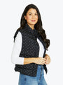 Woman wearing a black polka dot vest over a white shirt with a white background
