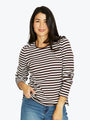 Woman wearing a black and white striped shirt with blue jeans on a light gray background
