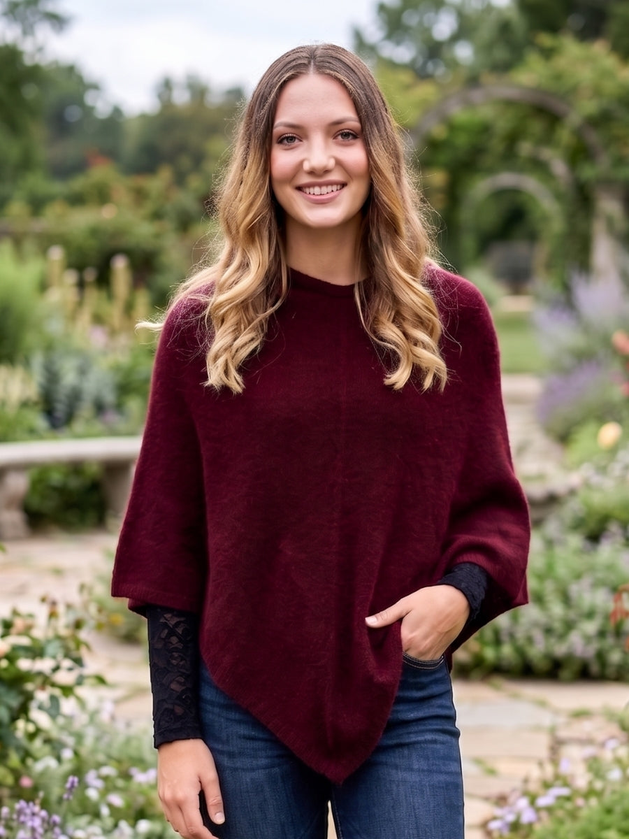 Woman wearing a maroon poncho in a garden setting