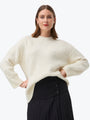 Woman wearing a cream sweater and black skirt on a white background