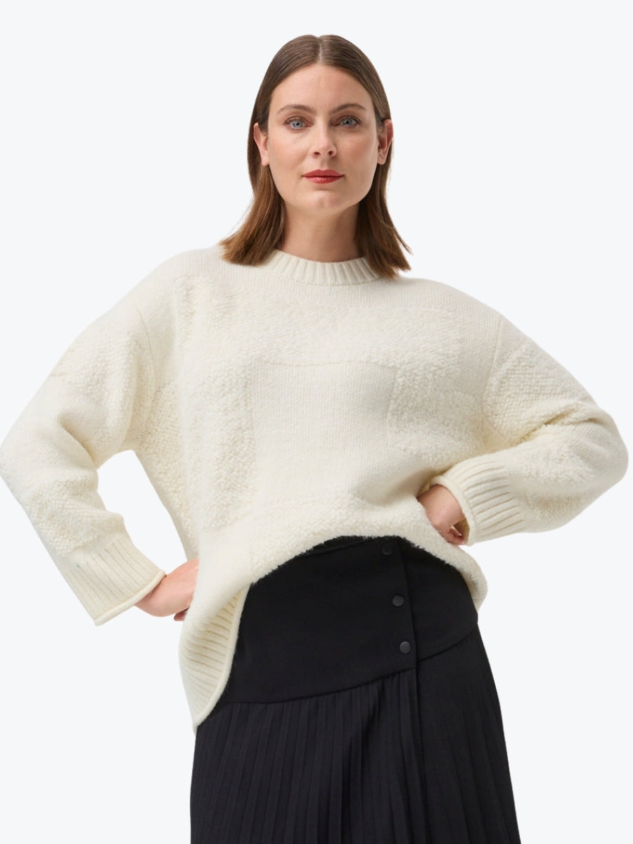 Woman wearing a cream sweater and black skirt on a white background