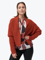 Woman wearing a red knitted cardigan over a patterned shirt on a white background