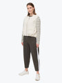 Woman wearing a striped sweater and dark pants with a white background