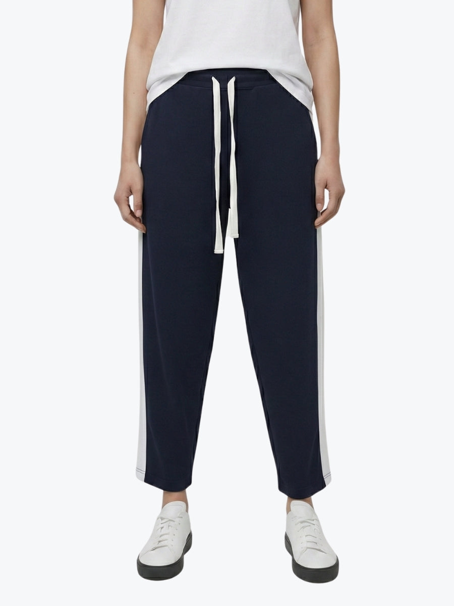 Person wearing navy pants with white drawstring and trim on a white background