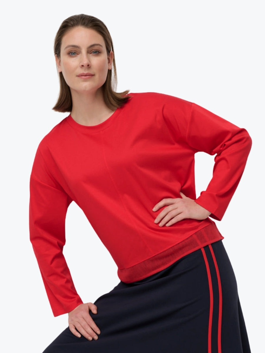 Woman wearing a red long-sleeve top and navy skirt with red stripes on a white background