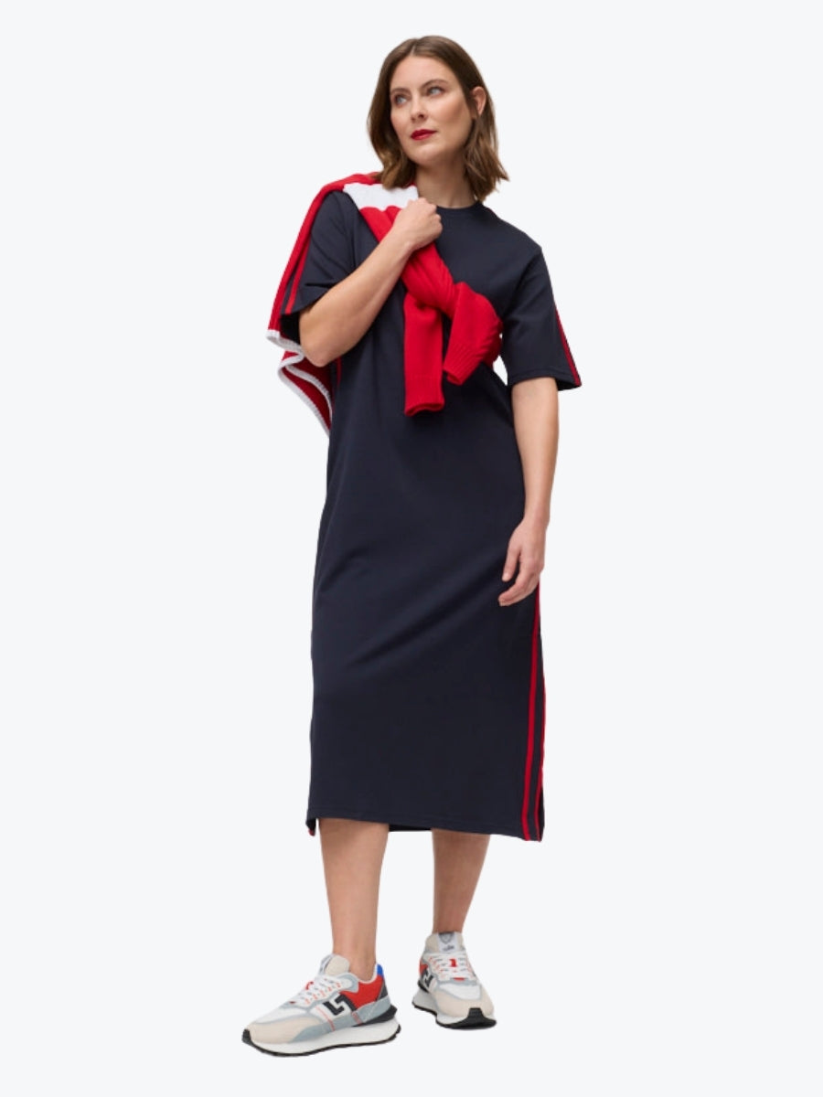 Woman wearing a navy dress with red accents on a white background