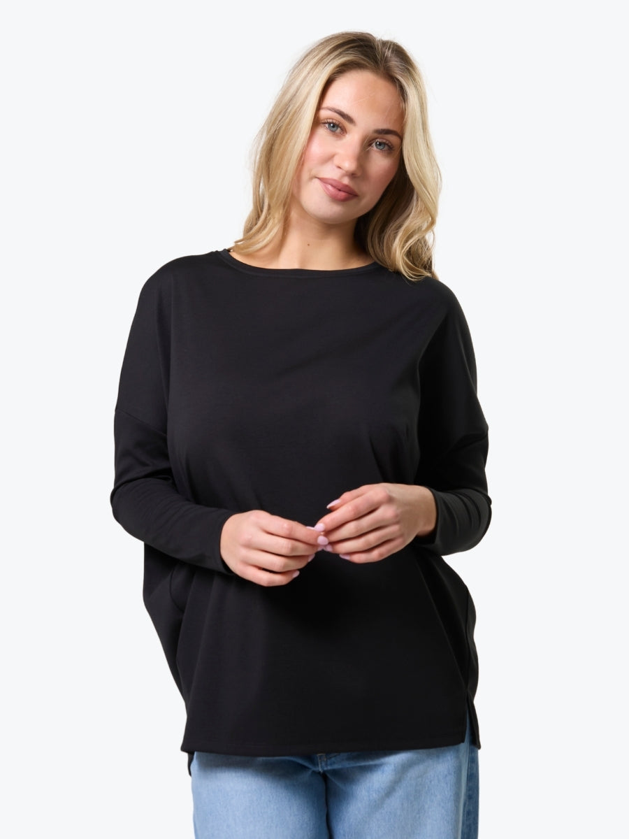 Woman wearing a black long-sleeve top against a white background