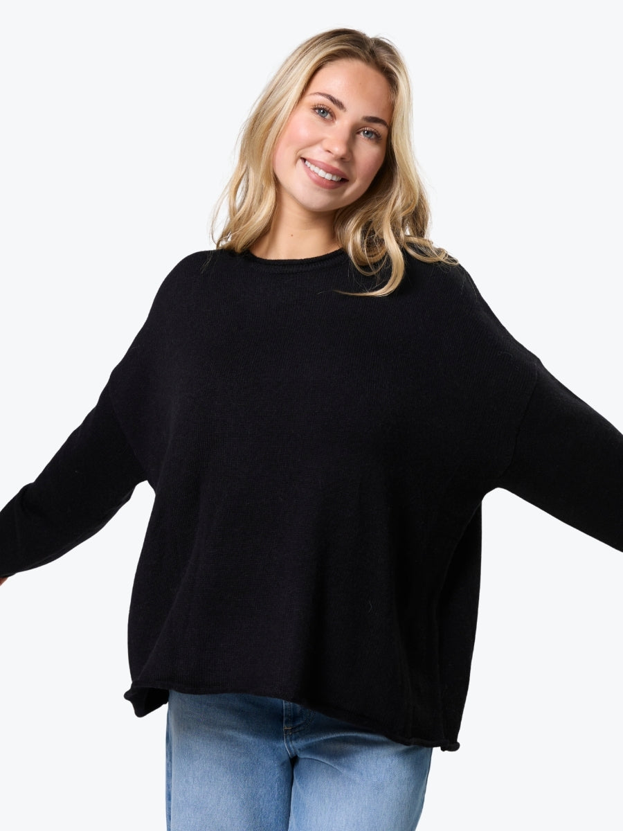 Woman wearing a black sweater and blue jeans on a white background