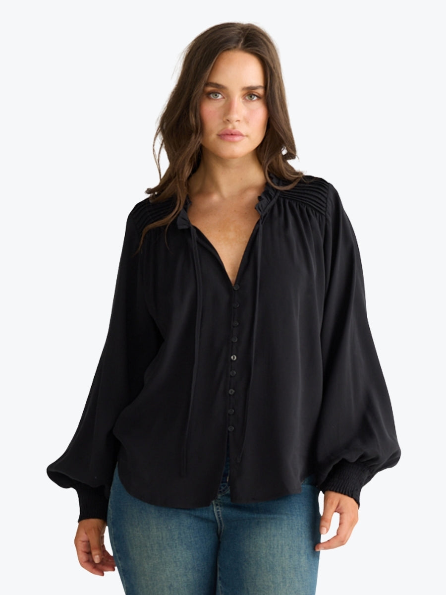 Woman wearing a black blouse with wide sleeves on a white background