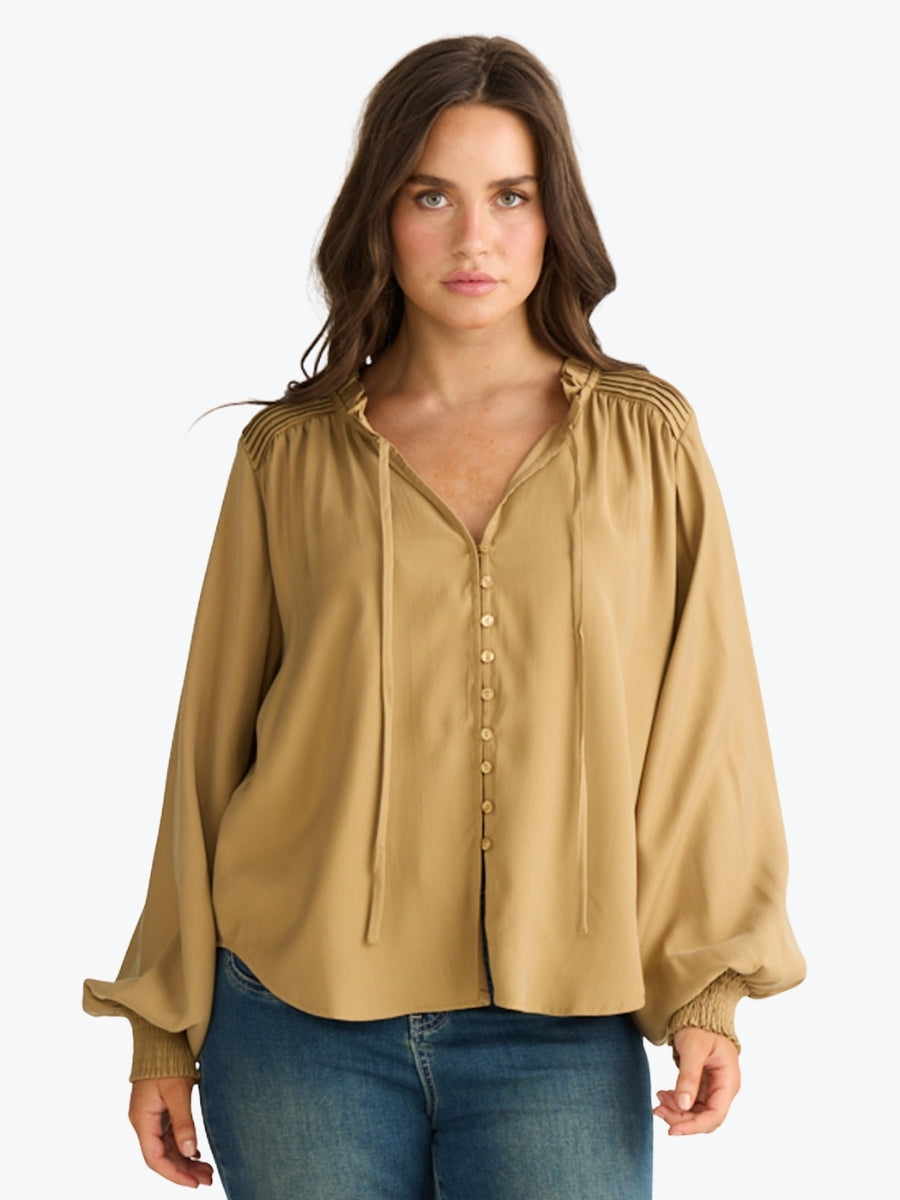 Woman wearing a beige blouse with long sleeves on a white background