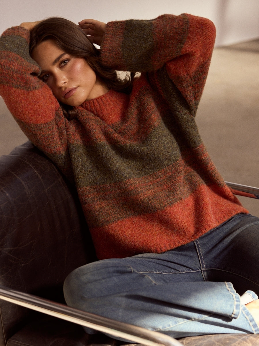 Person wearing a patterned sweater sitting on a chair.