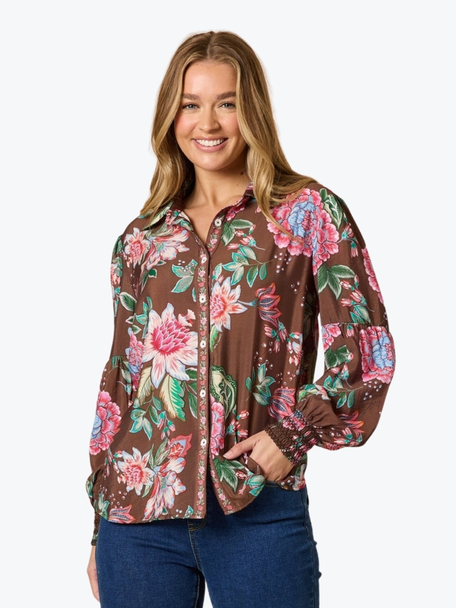 Woman wearing a brown floral blouse with a white background