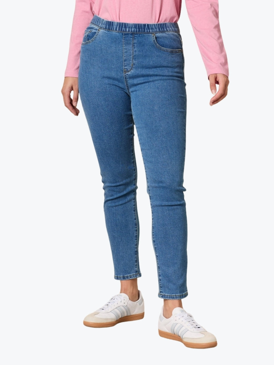 Person wearing blue jeans and a pink shirt on a white background