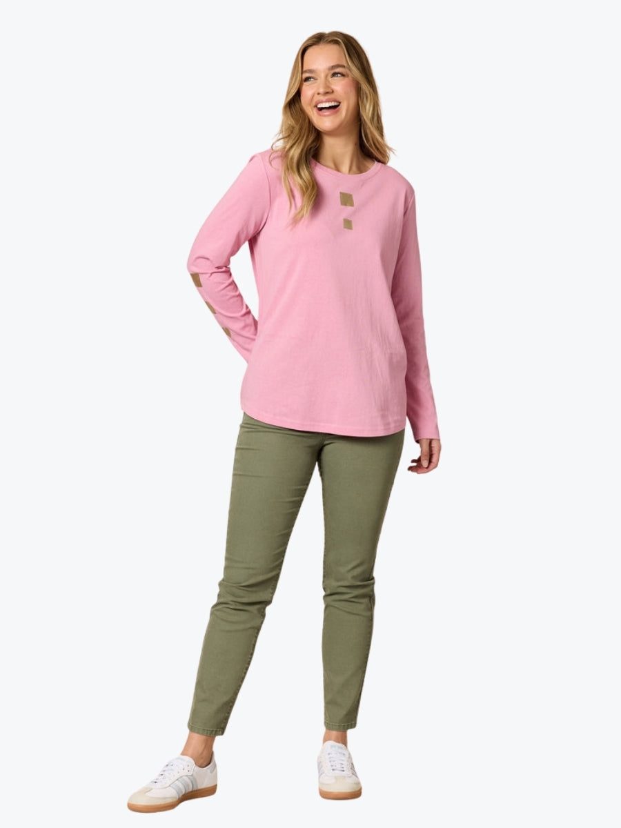 Woman wearing a pink long-sleeve shirt and green pants on a white background