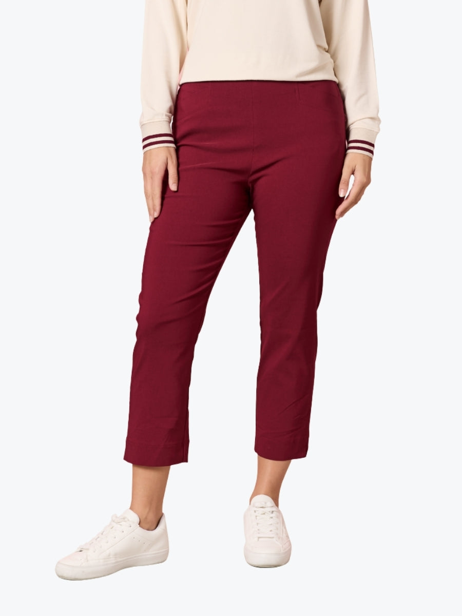 Person wearing burgundy pants and a cream top on a white background
