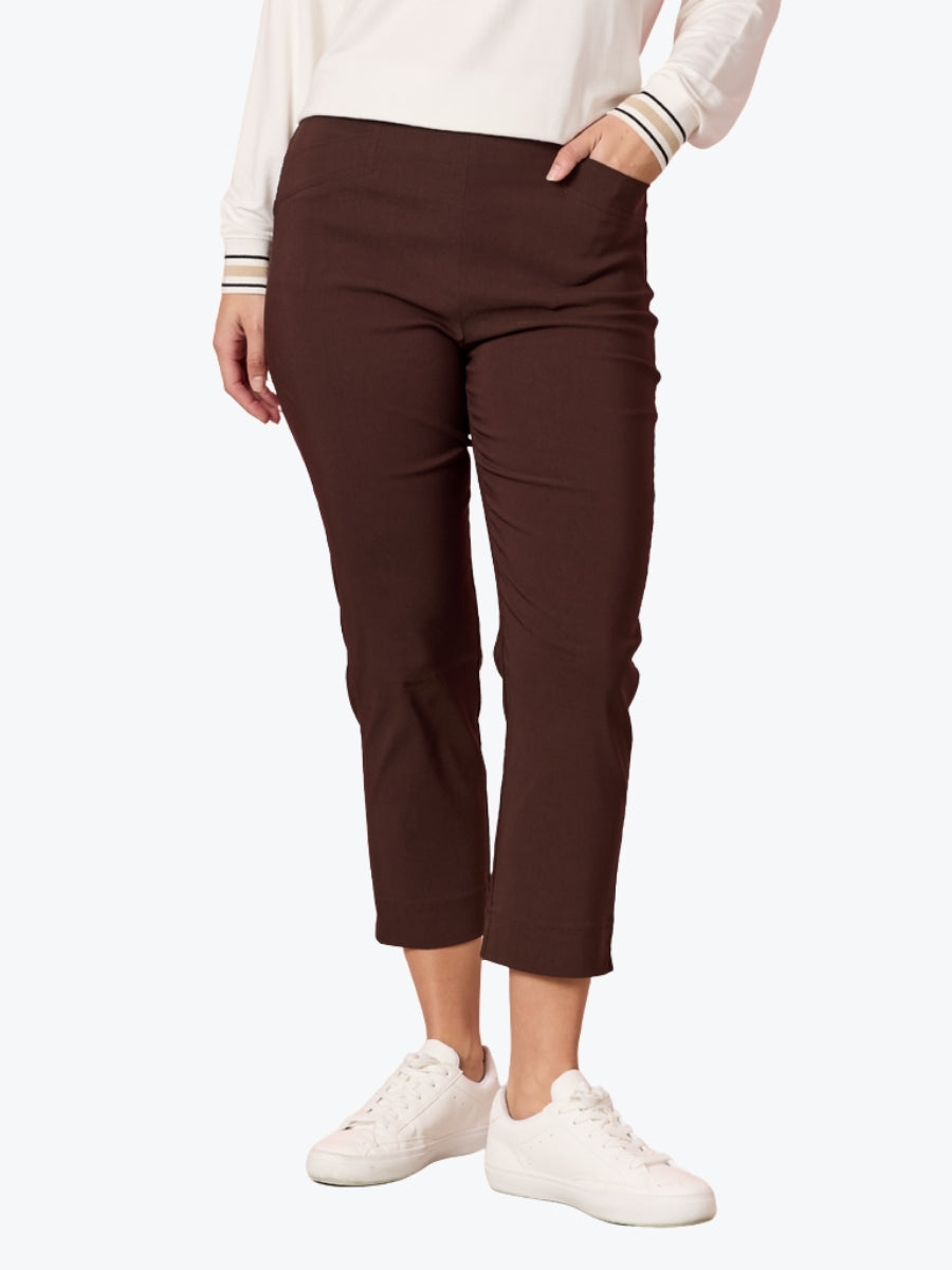 Person wearing brown pants and white sneakers on a white background