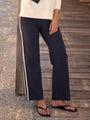 Navy pants with white stripes worn by a person on a wooden deck.