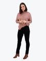 Woman wearing a pink sweater and black pants on a white background