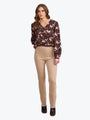 Woman wearing a floral blouse and beige pants on a white background