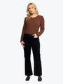 Woman wearing a brown top and black pants on a white background