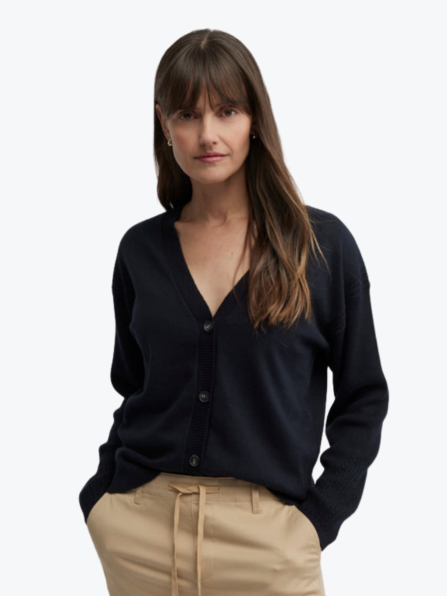 Woman wearing a black cardigan over a beige top on a white background