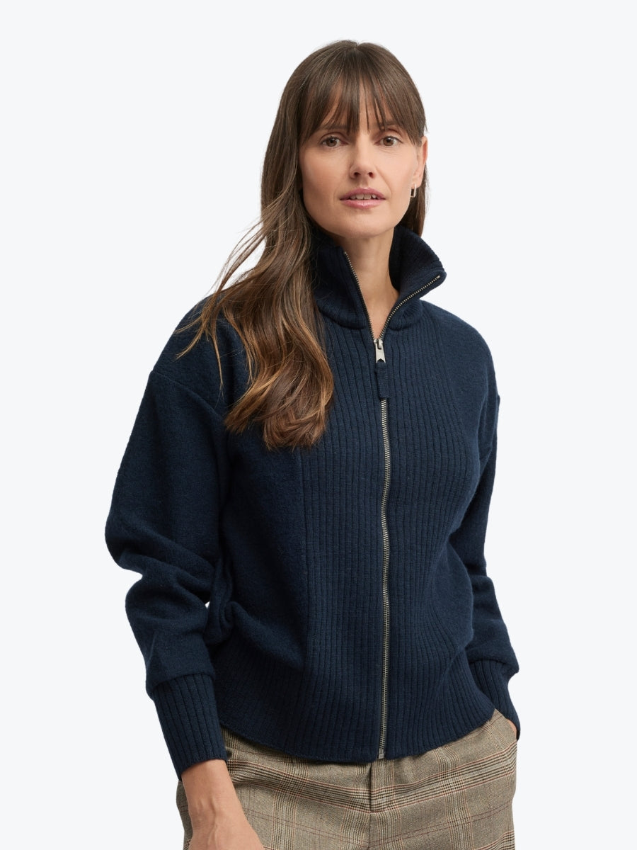 Woman wearing a navy blue zip-up sweater on a white background