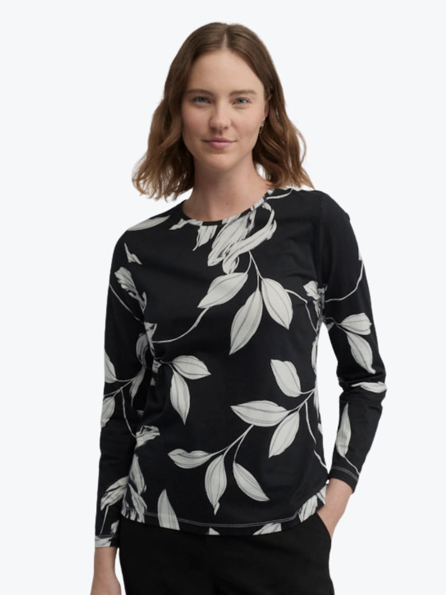 Woman wearing a black long-sleeve top with white leaf pattern on a white background