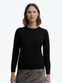 Woman wearing a black long-sleeve top with a white background