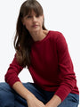 Woman wearing a red sweater sitting against a white background